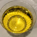 Aceite vegetal comestible, de color amarillo claro, en una taza de vidrio transparente