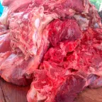 Trozos grandes de carne de res cruda apilados sobre la mesa de madera de una carnicería