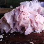 Filetes de tilapia crudos, blancos y rosados, amontonados sobre una mesa de madera