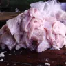 Filetes de tilapia crudos, blancos y rosados, amontonados sobre una mesa de madera