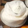 Harina de maíz blanca a granel en un costal abierto, con un tazón lleno encima, en un mercado