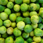 Limones con semilla verdes y amarillos amontonados, como se venden a granel en el mercado