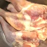 Piernas con muslo de pollo crudas, con piel, dentro de un recipiente de metal