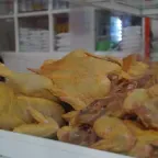 Pollos enteros crudos, de piel amarilla, acomodados en la vitrina de un puesto de mercado