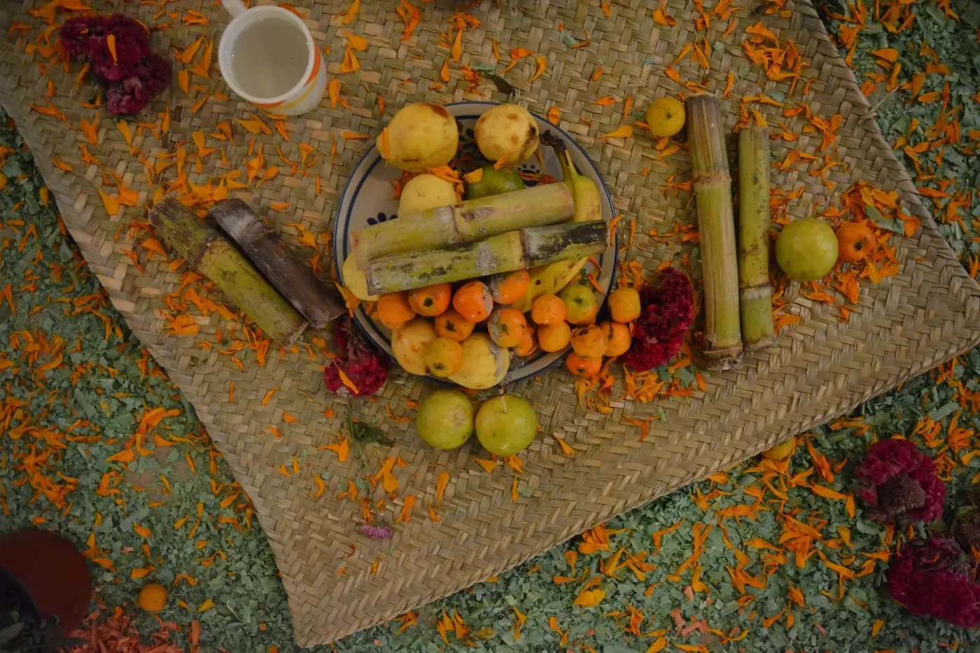 Tejocotes, guayabas y trozos de caña sobre un petate con pétalos de cempasúchil, fruta típica de la ofrenda de Día de Muertos